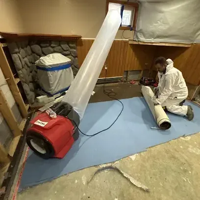 A technician hanging plastic containment and placing a dehumidifier in a room