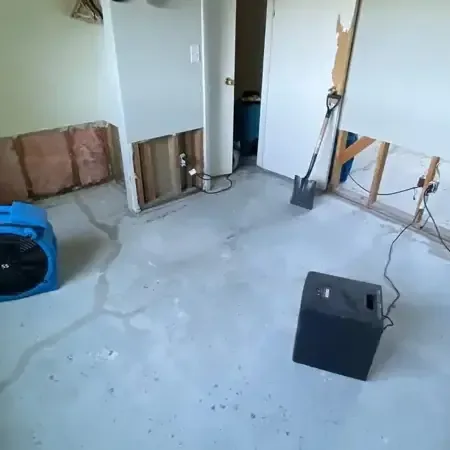Air movers and a dehumidifier set up to dry a water damaged room, with wet materials removed