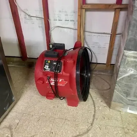 Technician placing an air mover beside an opened wall during a water damage job