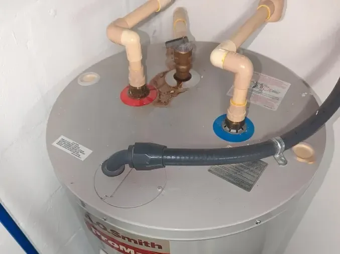 A tank water heater standing in a utility closet